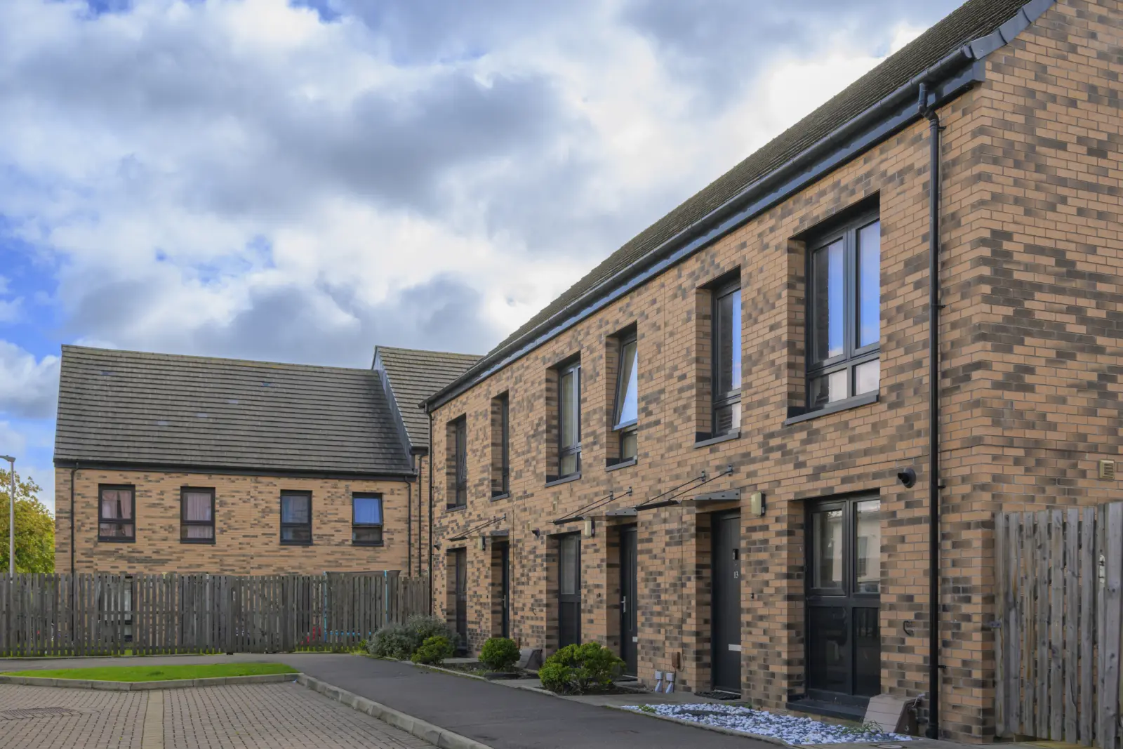 A terrace of new brick houses under a cloudy sky