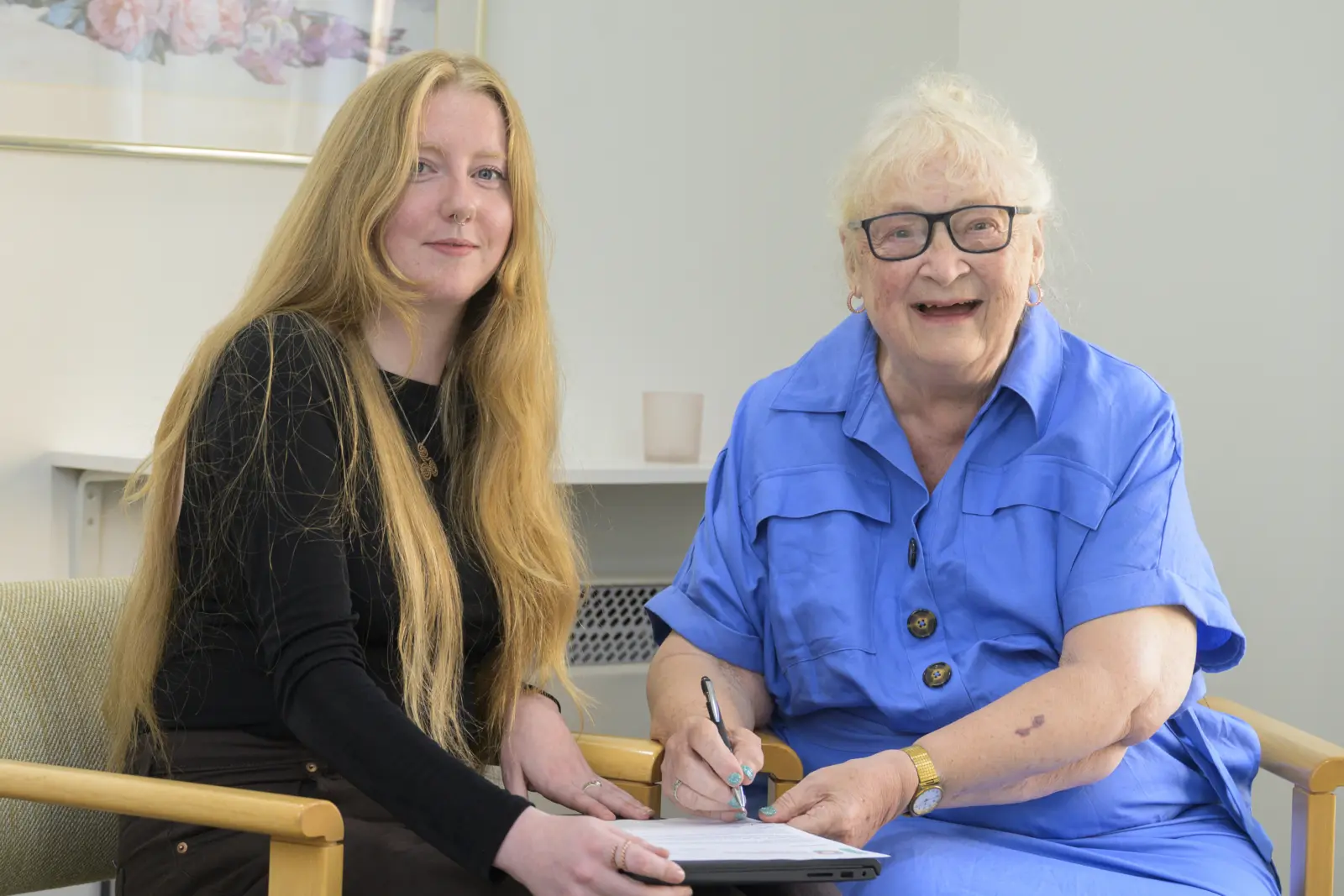 A Housing Options Scotland broker and an older client smiling as they fill in a form together