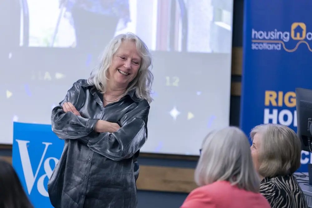 A guest smiling at the Housing Options Scotland 25th anniversary event at the V&A Dundee