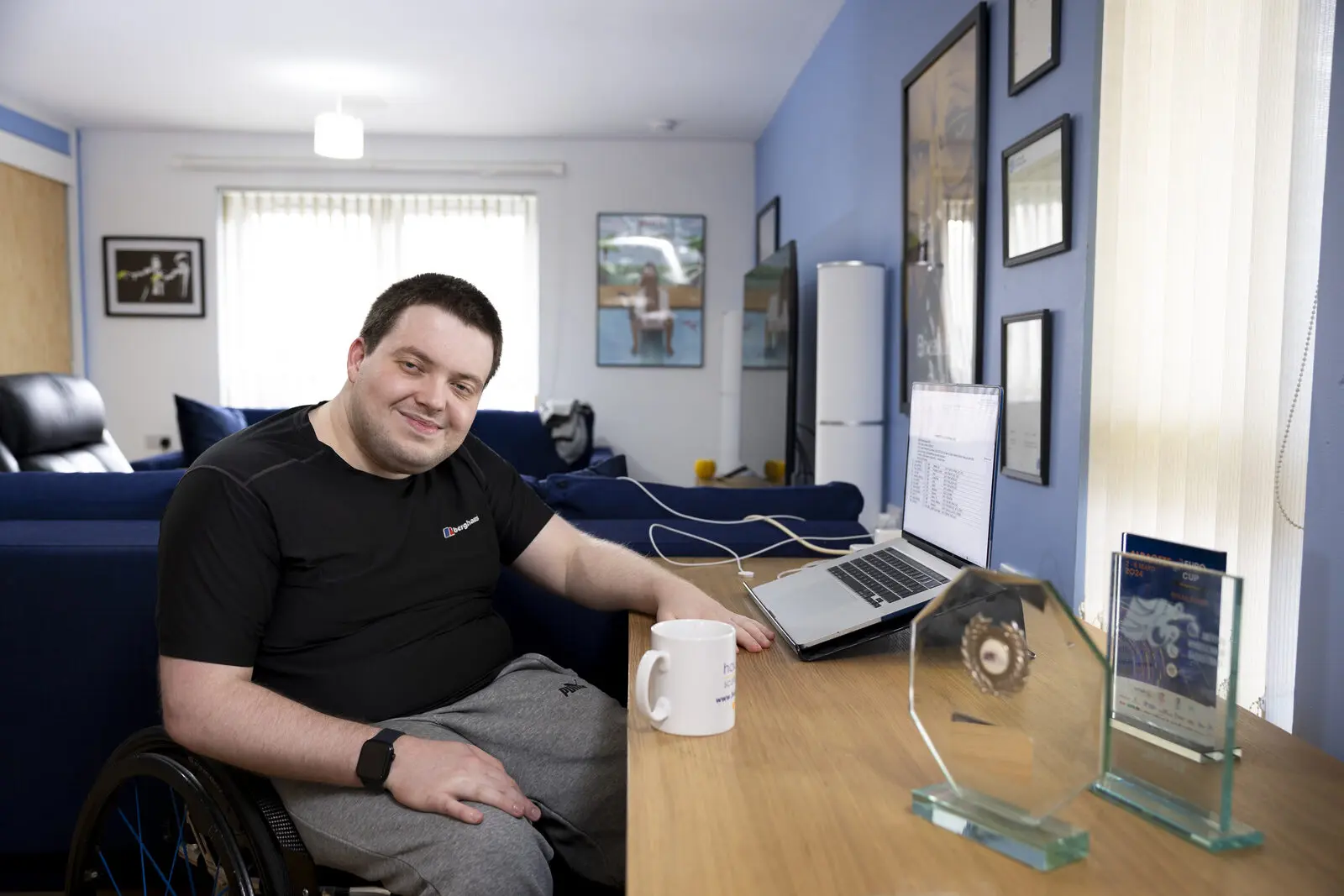 A young man in a wheelchair working at a laptop at his dining table