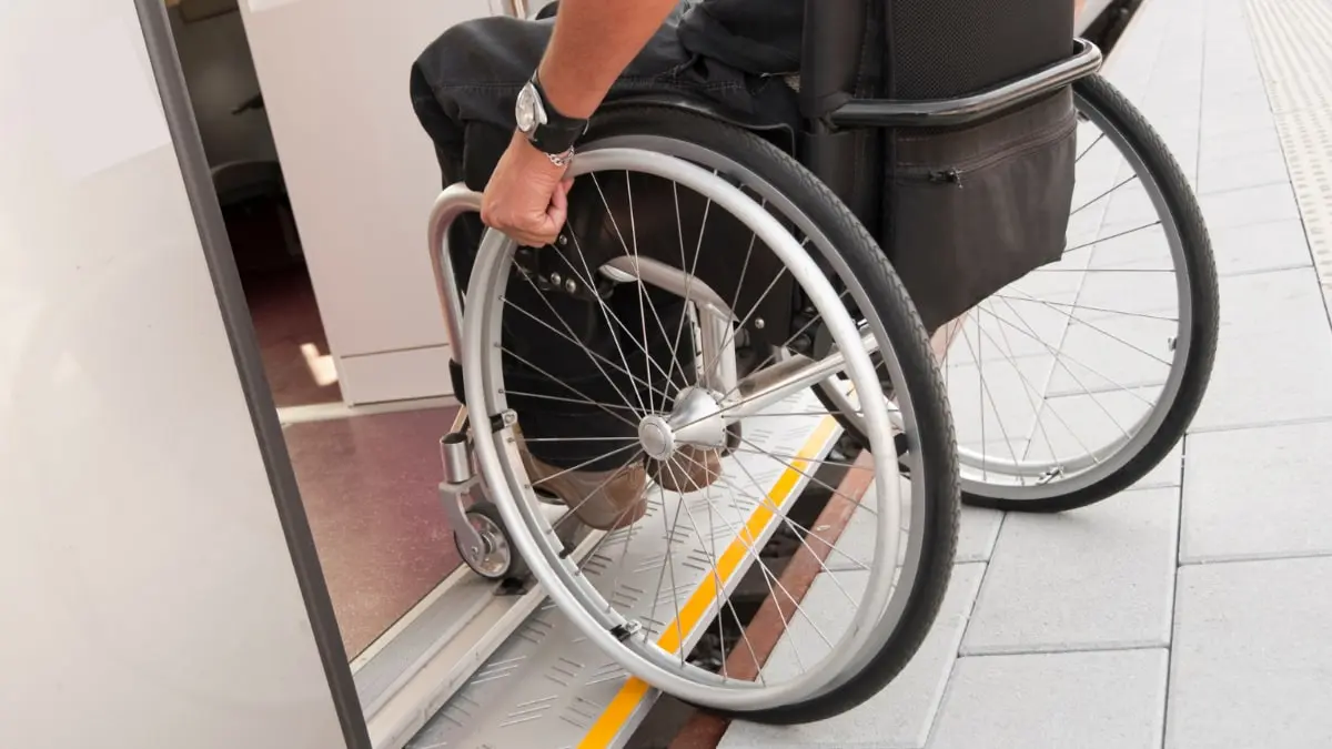 A wheelchair user wheeling over a low ramp through a doorway